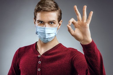 handsome man showing okay gesture. photo of healthy man wears protective mask against infectious diseases and flu. health care concept.