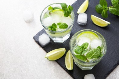 cold refreshing summer lemonade mojito in a glass on a slate board and stone background