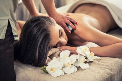 young woman enjoying the therapeutic effects of a traditional hot stone massage at luxury spa and wellness center