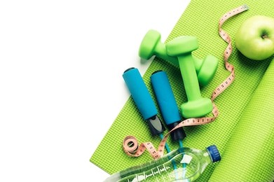 fitness concept - yoga mat, apple, dumbbells and skipping rope on the white background