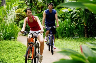 couple cycling through a park, smiling