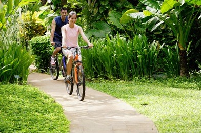 young couple cycling through a park, smiling