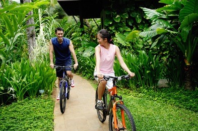 couple cycling on a path through a park