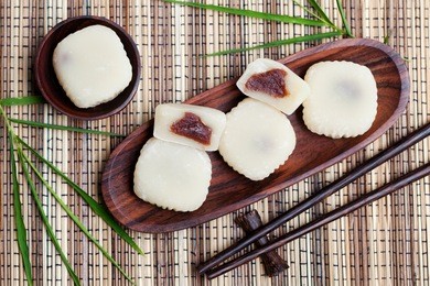 mochi cake with red beans on wooden plate with bamboo leaves. traditional japanese dessert. top view.