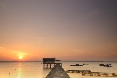 sunset landscape scenery of a beach house and a long jetty with the sun setting at the background at ekas beach, lombok island, indonesia. 