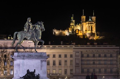 place bellecour statue of king louis xiv and the basilica notre dame de fourviere on the background at night. lyon france