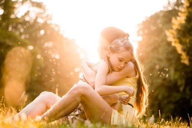 mother is cuddling her worried child outdoor in nature