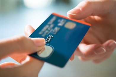 closeup shot of a woman passing a payment credit card to the seller. girl holding a credit card. shallow depth of field with focus on the credit card.