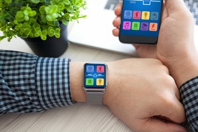 man hands holding watch and phone with app smart home on screen near laptop