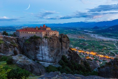 st stefan monastery in meteora rocks, meaning "suspended into air" in trikala, greece with the moon rising above the sky