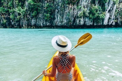 woman paddling a kayak in the island lagoon between mountains. kayaking in el nido, palawan, philippines.