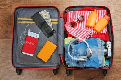 open suitcase with travel accessories on wooden floor