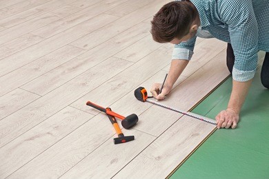 man installing new wooden laminate flooring