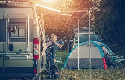 camping family time. father playing with his daughter around camper van rv and tents. family on the campground.