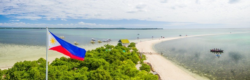 the philippine flag flying above the virgin island located near panglao, bohol, philippines.