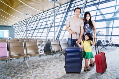 image of asian family carrying suitcases for holiday while  standing in the airport terminal 