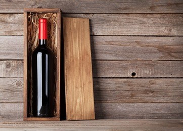 red wine bottle in box in front of wooden wall. with copy space