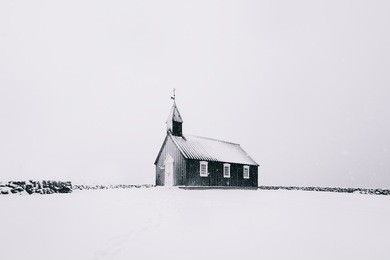 beautiful minimalistic view of budir black church in the snaefellsnes peninsula during severe snowstorm