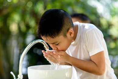 selective focus brand new faucet and kid hand taking water to wash.
