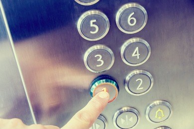 finger presses on first floor in modern metal elevator business building