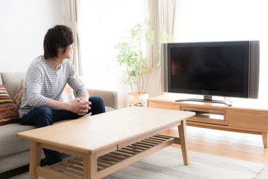 young asian man watching tv in  the living room