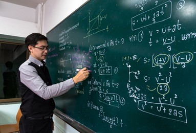 asian teacher writing the physics formula in thai language on black board in school classroom, school education concept