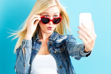young woman taking a selfie on a blue background