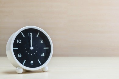 closeup alarm clock for decorate in 12 o'clock on brown wood desk and wall textured background with copy space