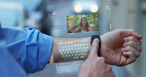a man answers the wife who smiles and waves from the phone that appears in hologram clock futuristic and technological. concept: network, communication,family, technology, augmented reality and future