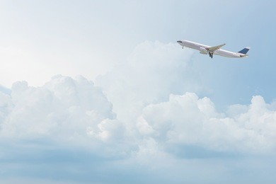 commercial airplane flying over bright blue sky and white clouds. elegant design with copy space for travel concept.