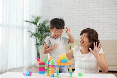 asian little boy and his mother playing with blocks and having fun