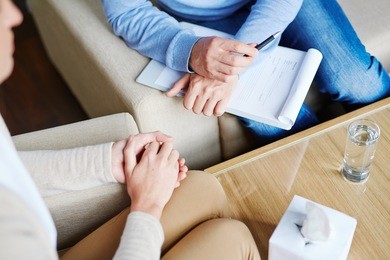 middle-aged psychologist sitting next to his patient and listening to her childhood story in order to find reason of her disease