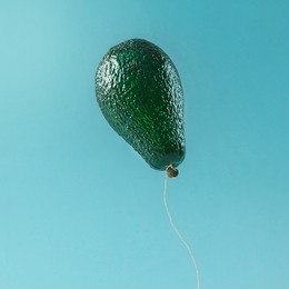 balloon made of avocado fruit on blue background. minimal fruit concept.