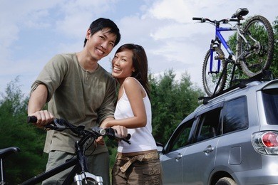 man on a bike, woman standing next to him, looking at camera