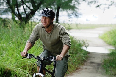 man cycling on nature path, smiling
