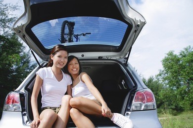 young women sitting in boot of car, portrait