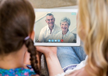 woman and girl having a video call with senior couple on digital tablet at home