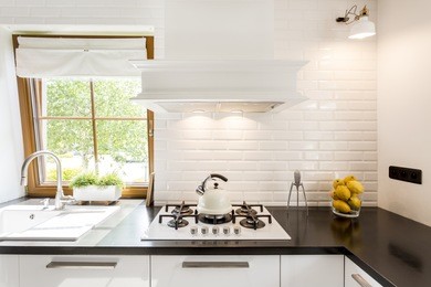 cropped shot of a bright kitchen room designed in white with a black countertop