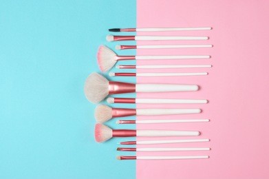 set of makeup brushes on pink and aqua colored composed background. top view point, flat lay.