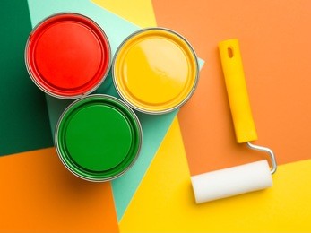 three cans  yellow green and red and paint roll on colourful geometrical background