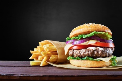 craft beef burger and french fries on wooden table isolated on black background.