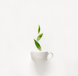 cup of fresh green tea with green leaves rising above, tea aromatic qualities concept