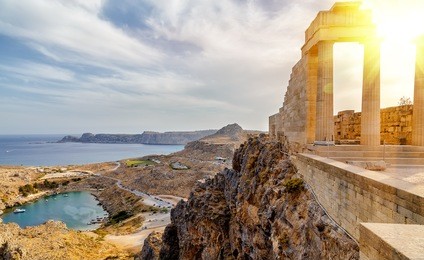 greece. rhodes. acropolis of lindos. doric columns of the ancient temple of athena lindia setting sun above the columns