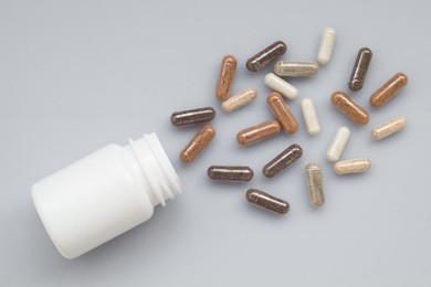 medicinal capsule spill out of a plastic bottle on a light surfa