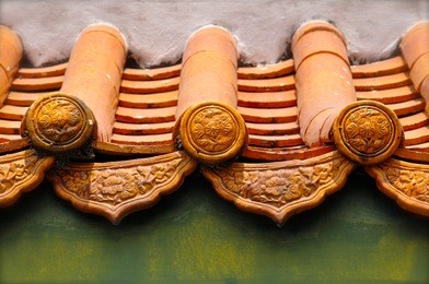 tiled roof of a chinese temple, with parallel ridges of green clay tiles with decorative end tiles at the eaves. 