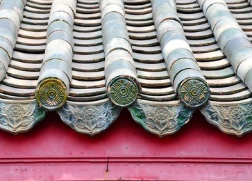 tiled roof of a chinese temple, with parallel ridges of green clay tiles with decorative end tiles at the eaves. 