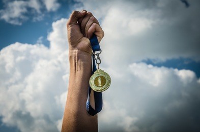 hand in hand with the medal 1st place winner success against the sky clouds