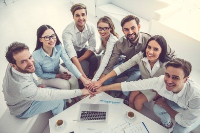 business team is using putting hands together and smiling while working in office