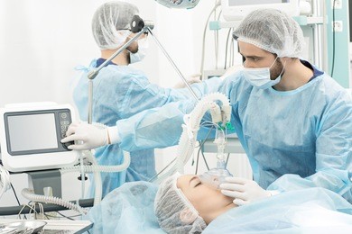 surgery preparations. surgical team preparing their patient for surgery adjusting oxygen mask checking monitors at the operating room healthcare medicine professionalism teamwork doctors copyspace 