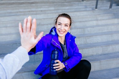 first person view of a man and woman high fiving. happy young woman giving high five to man after outdoor training. couple of runner on country road looking happy.
